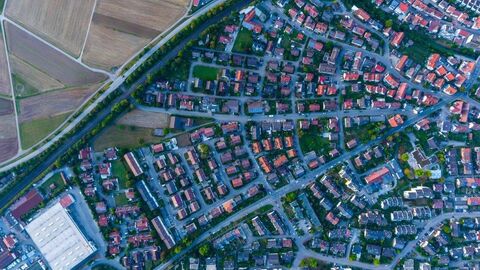 Gemeinde von oben Blick aus der Vogelperspektive auf eine Stadt mit vielen Häusern, Straßen, Gärten und Bäumen. Eine Umgehungsstraße und Felder sieht man im linken oberen Teil des Bildes an die Stadt grenzend.